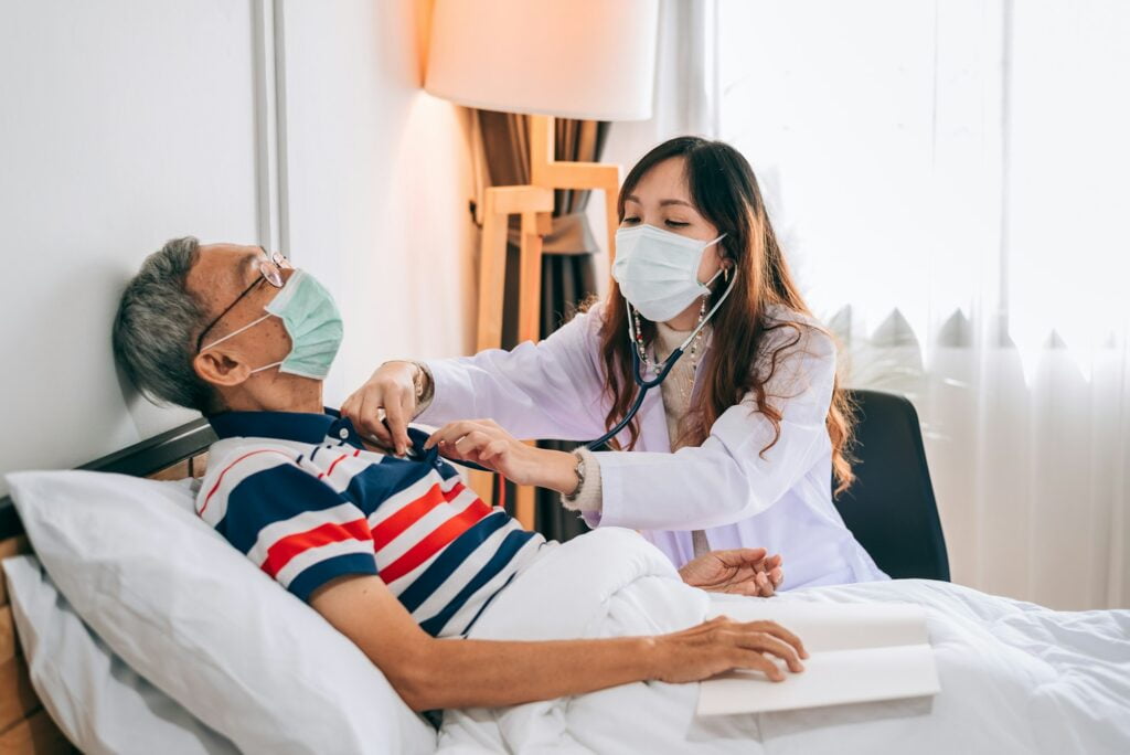 Asian doctor using a stethoscope to examines a senior man at home ,The doctor checking up.